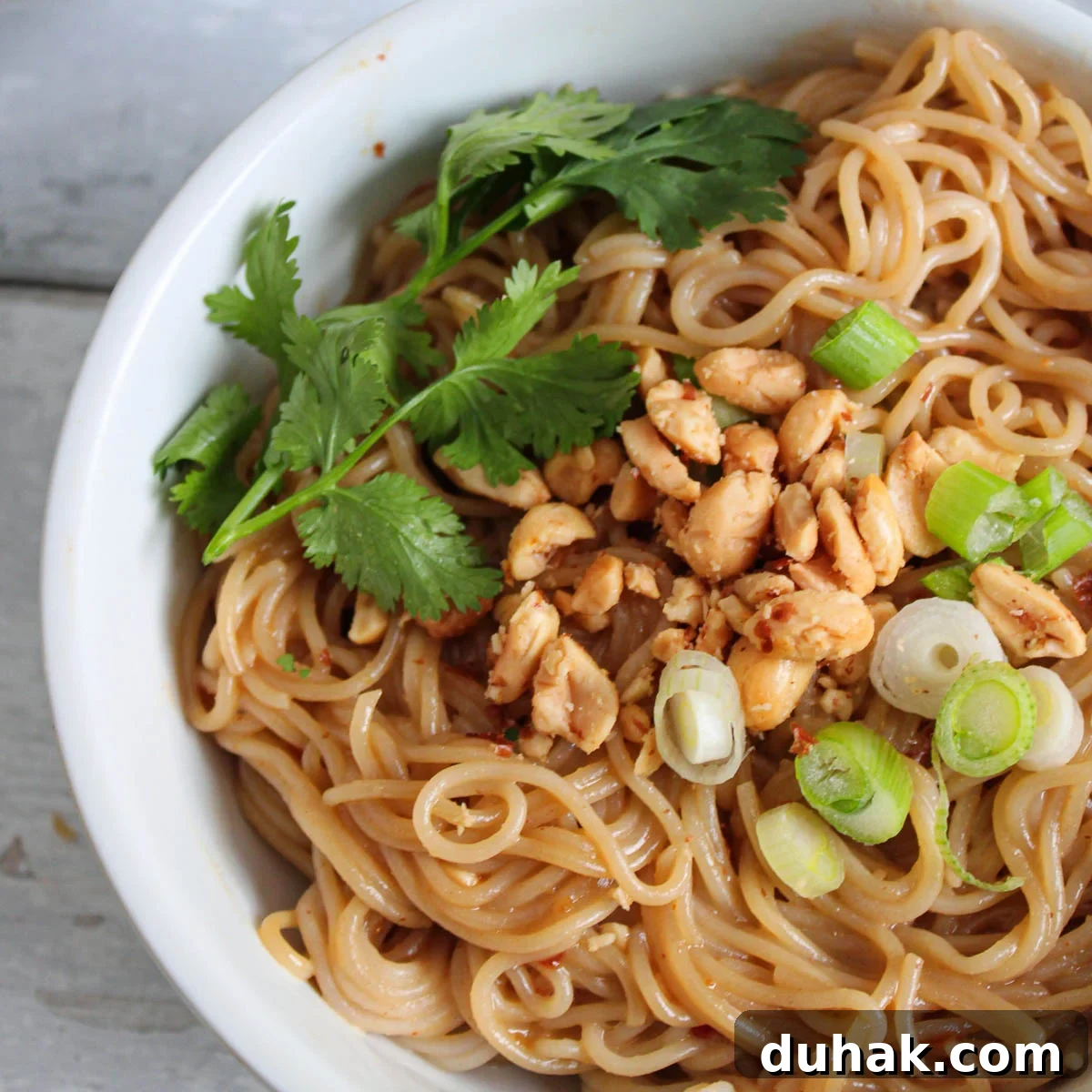 Bowl of thai peanut butter ramen with garnishes on top. 
