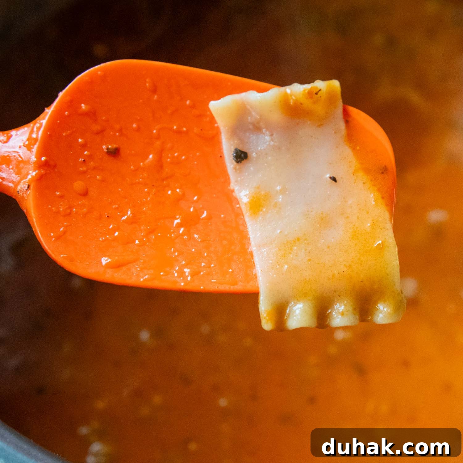 30-Minute Gluten-Free Lasagna Soup Recipe — Hearty & Homemade 4 orange spoon lifting a lasagna noodle out of soup to be checked for doneness.