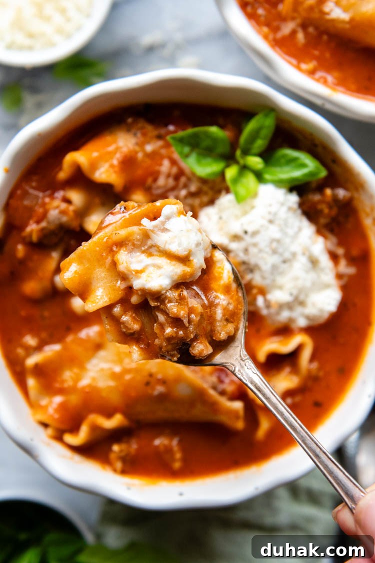 30-Minute Gluten-Free Lasagna Soup Recipe — Hearty & Homemade 7 White bowl filled with soup topped with ricotta topping and garnished with fresh basil.
