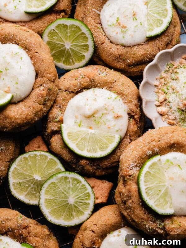 A close-up of the key lime pie cookies nestled together on a cooling rack, with slices of lime for garnish.