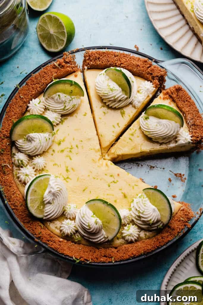 A bird's eye view of the sliced key lime pie in the pie dish. Each slice is topped with a swirl of whipped cream and a lime slice.