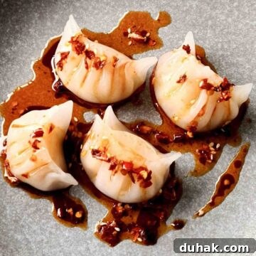 A plate of har gow drizzled with chili oil sauce