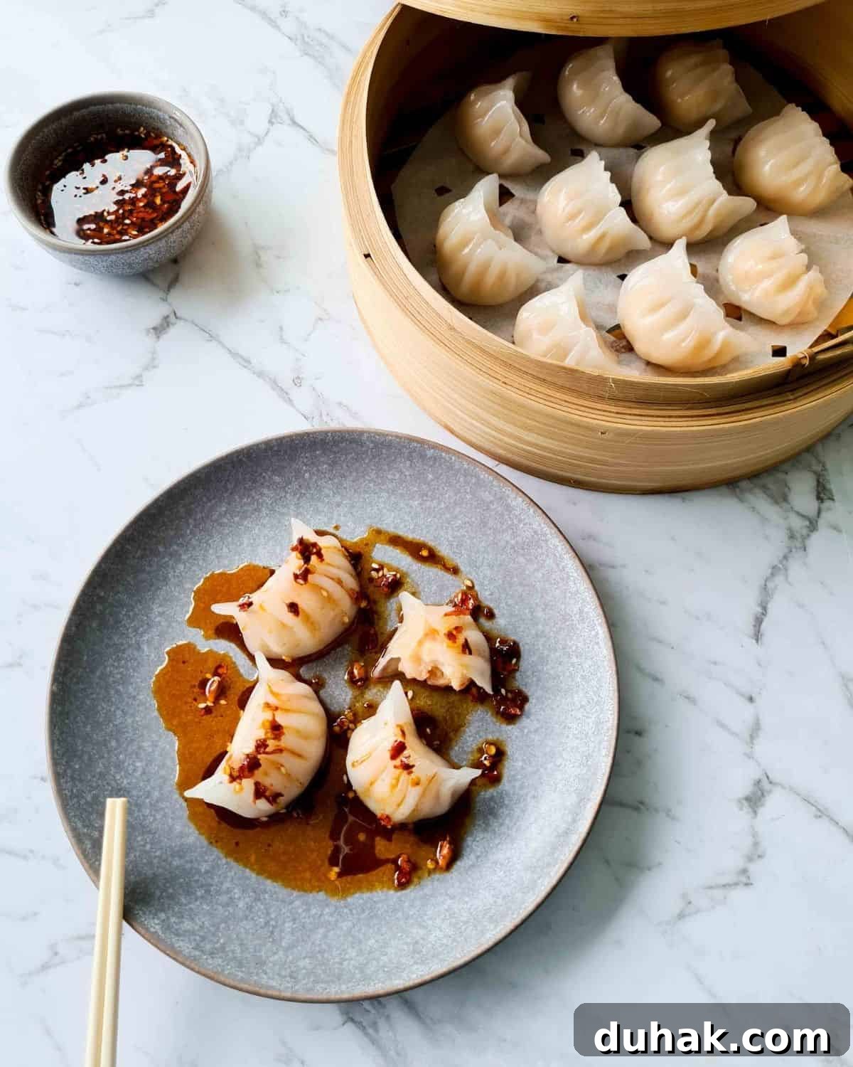 A small plate filled with 4 har gow drizzled with chilli oil dipping sauce
