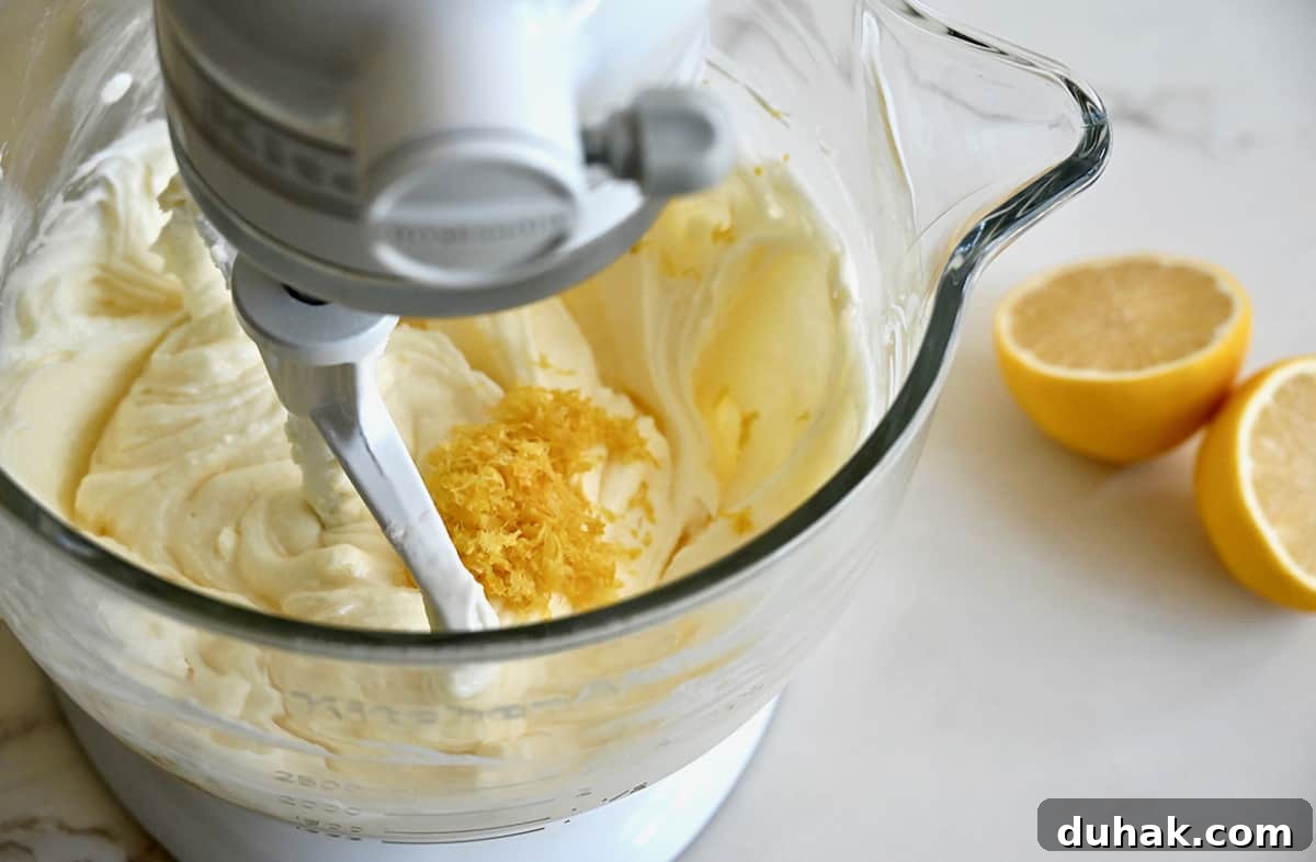 Glazed Lemon Pound Cake Recipe with Zesty Drizzle 4 A stand mixer bowl containing batter topped with citrus zest.