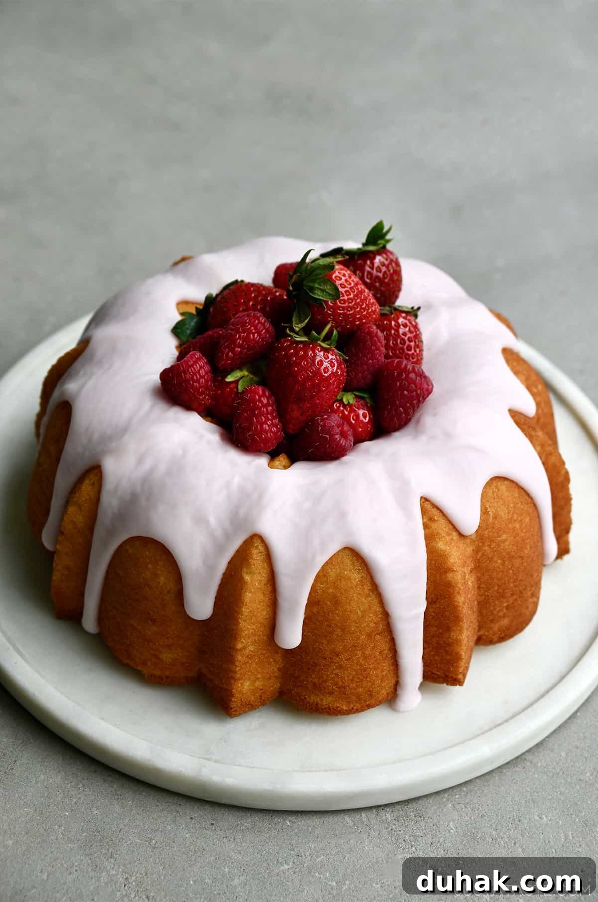 Glazed Lemon Pound Cake Recipe with Zesty Drizzle 8 A lemon bundt cake with strawberry glaze and fresh strawberries in the center.
