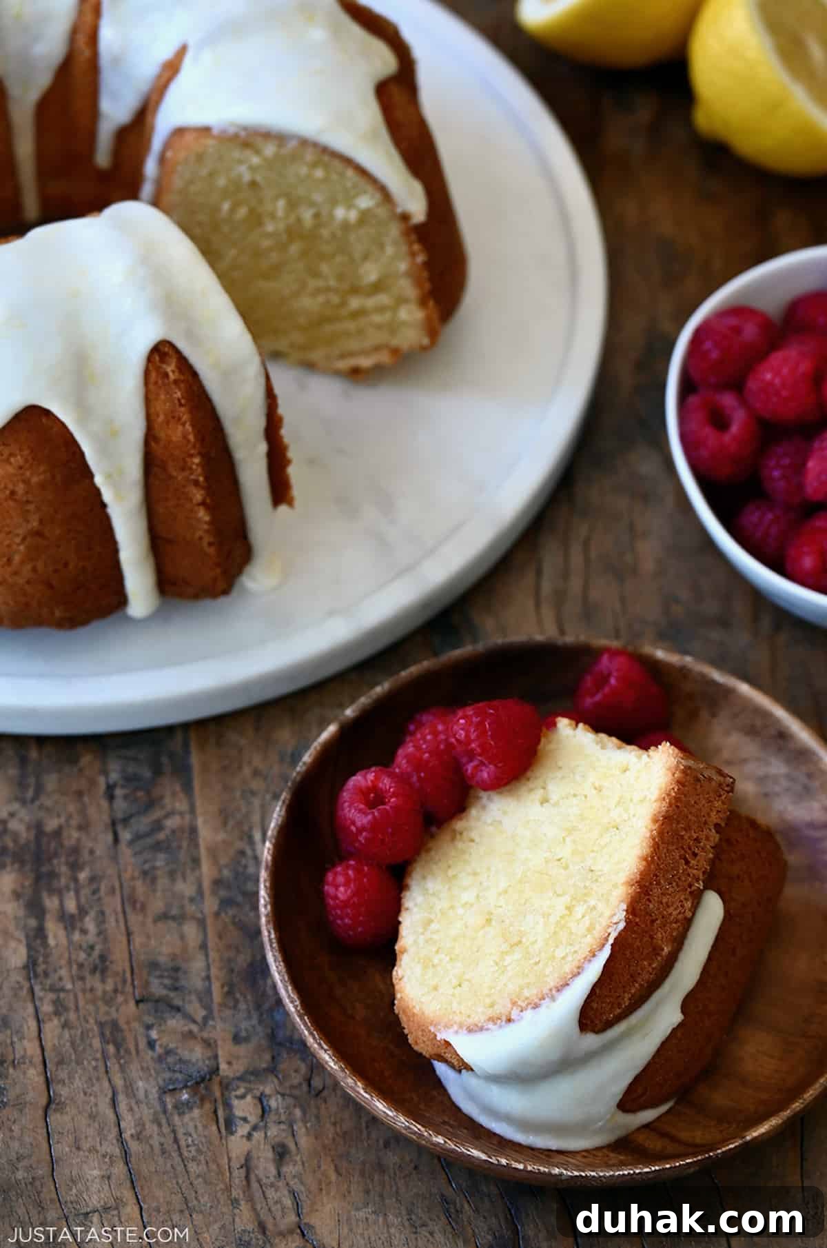 Glazed Lemon Pound Cake Recipe with Zesty Drizzle 9 A slice of lemon cream cheese pound cake on a plate with fresh raspberries.