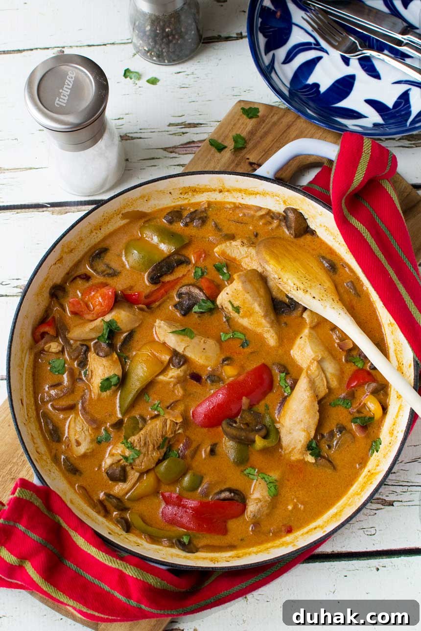 30 minute paprika chicken Paprika chicken in a cast iron pan from above on a wooden board and with a red tea towel.