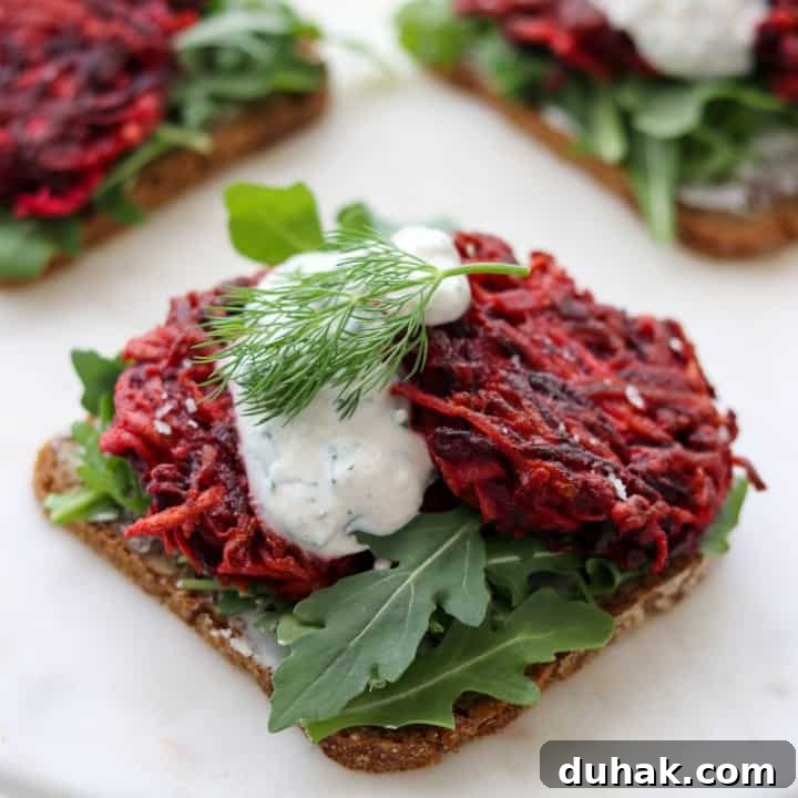 An open sandwich with beet and celery root cakes and creamy sauce on a plate
