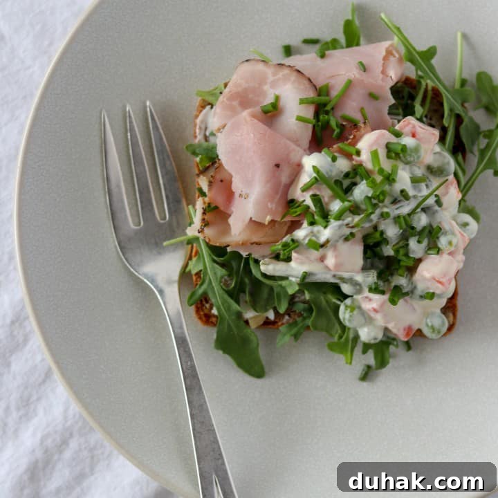 An open ham sandwich on a plate with a fork