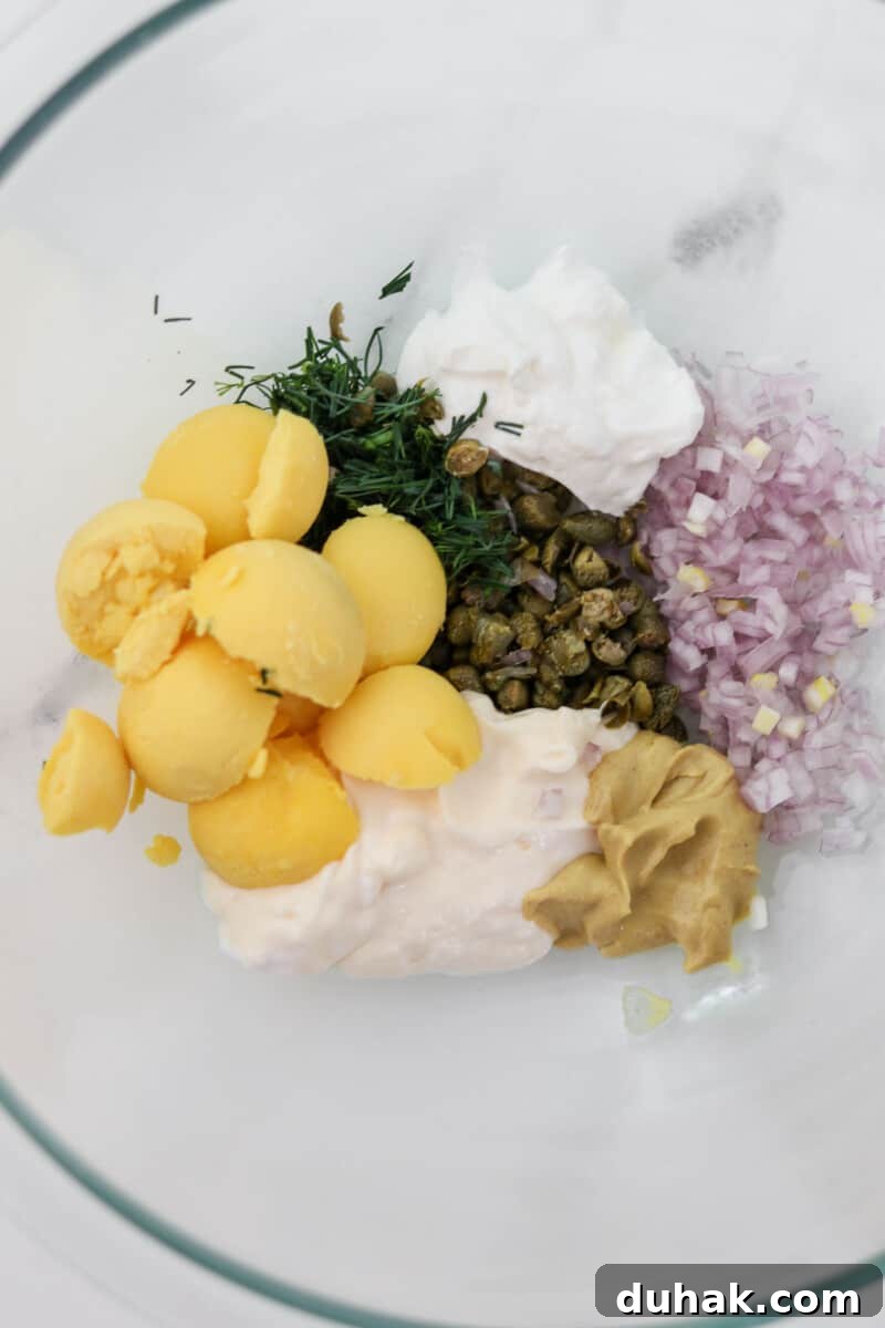 Creamy Egg Salad with Dill, Capers & Lemon Zest 6 Ingredients for egg salad in a bowl before being mixed.