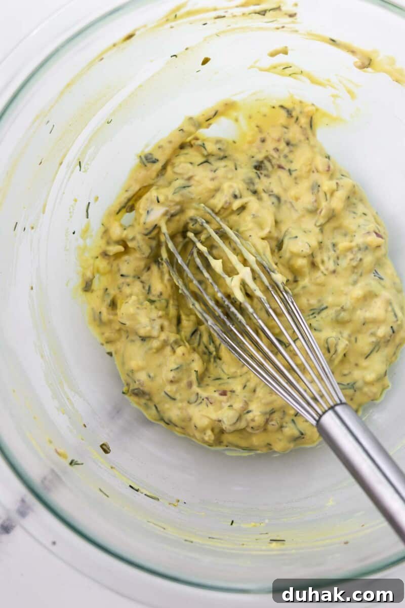 Creamy Egg Salad with Dill, Capers & Lemon Zest 7 Egg salad in a glass bowl with a whisk.