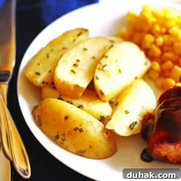 A plate with roasted potato wedges, corn, and bbq chicken.