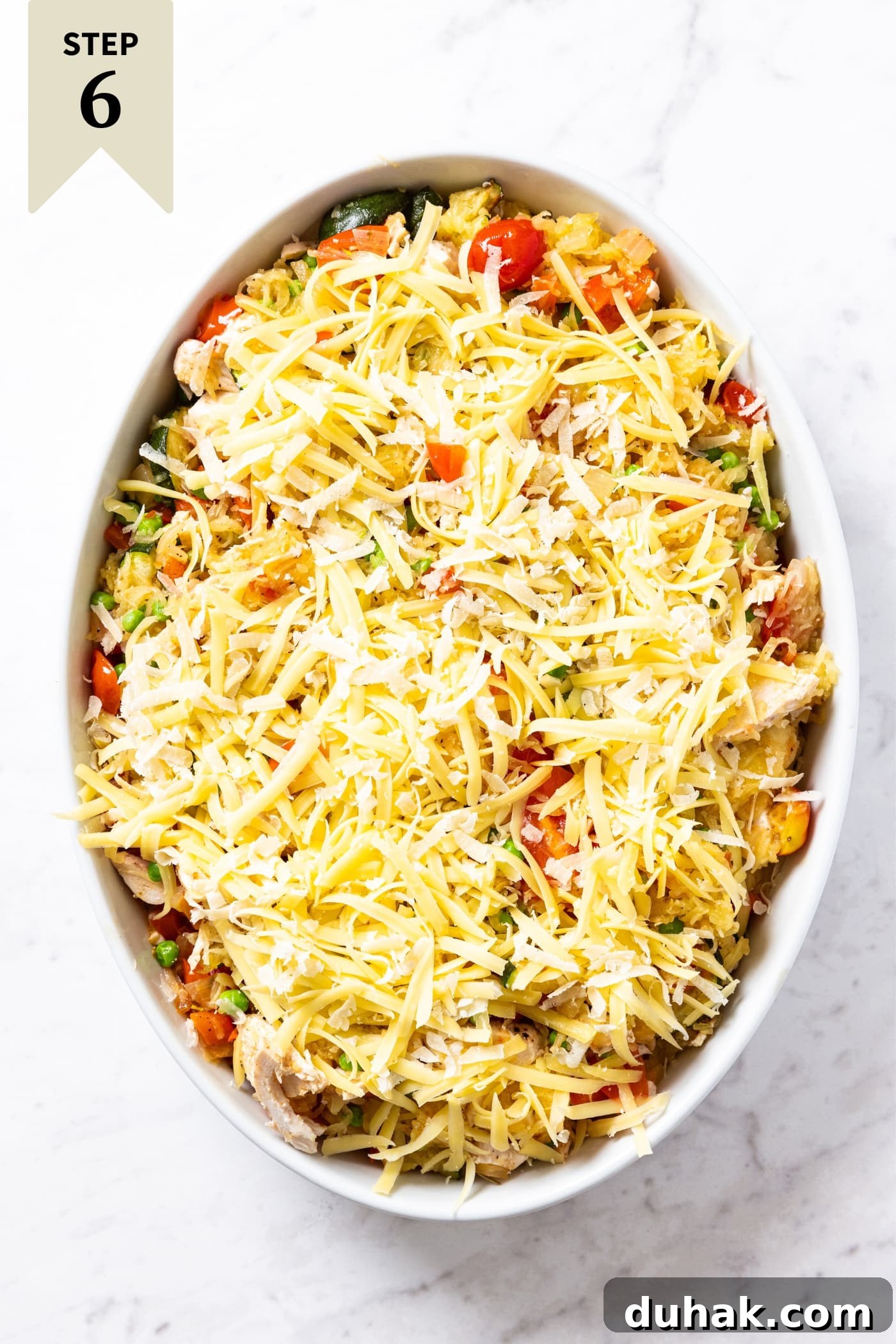 Cheesy Turkey & Spaghetti Squash Casserole Recipe 19 Oval white baking dish filled with unbaked spaghetti squash chicken casserole with tomatoes showing through and topped with unmelted mozzarella cheese right before going into the oven to bake.
