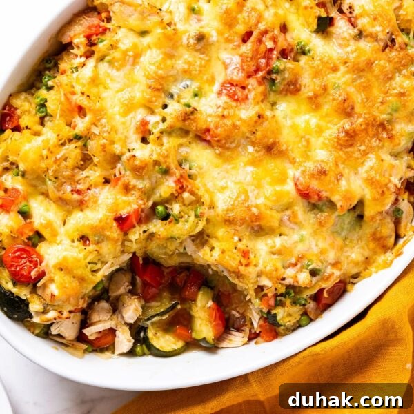Cheesy Turkey & Spaghetti Squash Casserole Recipe 22 White oval baking dish filled with baked spaghetti squash chicken casserole on white marble surface with melted cheese over the top.