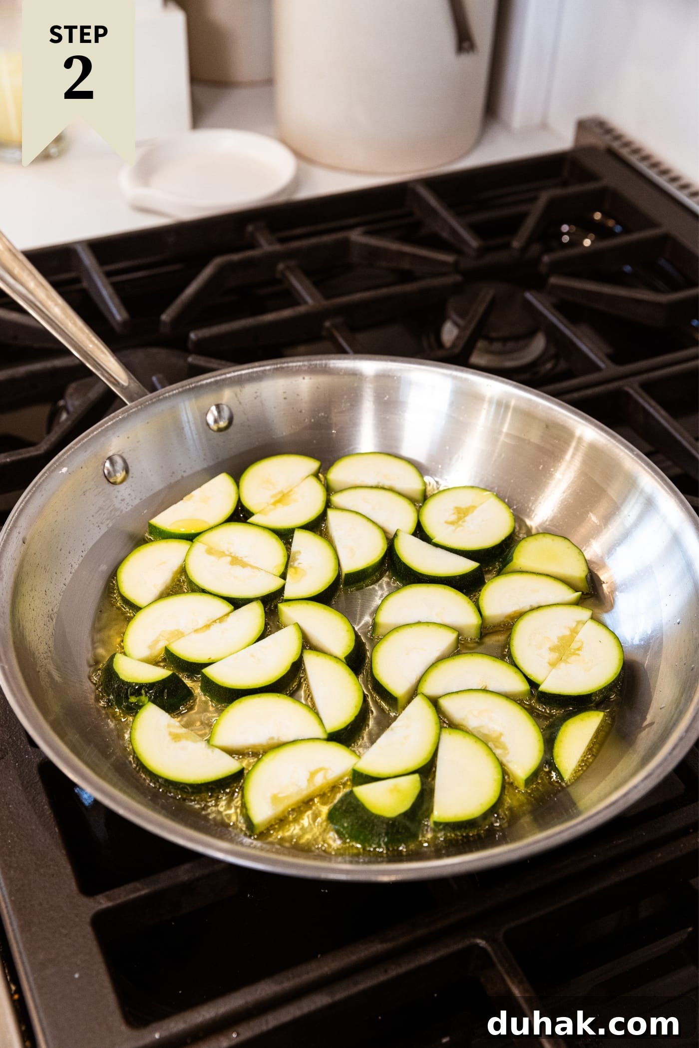 Cheesy Turkey & Spaghetti Squash Casserole Recipe 9 Metal skillet sitting on stovetop with uncooked half moons of zucchini sitting in hot oil on the heat.