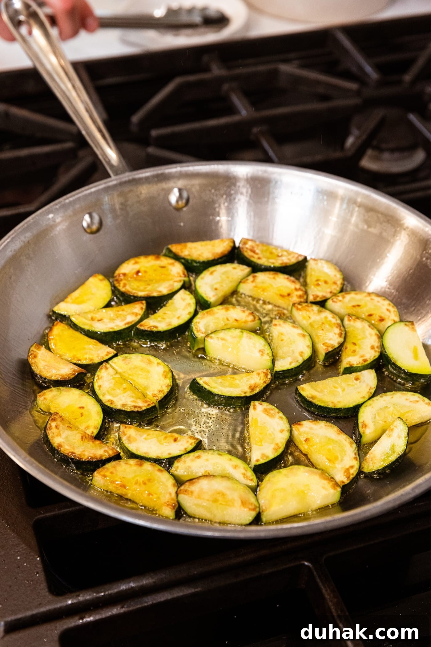 Cheesy Turkey & Spaghetti Squash Casserole Recipe 10 Browned half moons of zucchini sitting in metal skillet filled with oil over hot heat on stovetop.