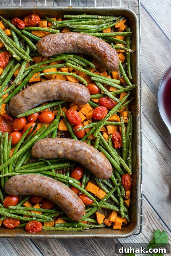 One-Pan Italian Sausage with Roasted Vegetables 6 A pan filled with an Italian sausage sheet pan dinner with roasted sweet potatoes, green beans, and cherry tomatoes, fresh out of the oven and ready to serve.