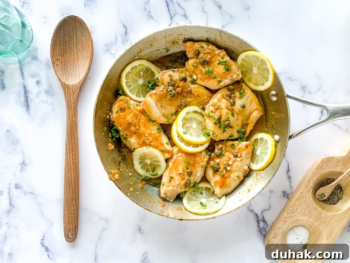 Cheesecake Factory Chicken Piccata Recipe: Copycat Instructions 3 Homemade version of chicken piccata Cheesecake Factory recipe shown in a large skillet garnished with lemon slices.