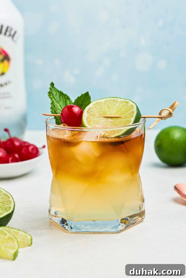 Bahama Mama Cocktail Recipe: Tropical Rum Drink Guide 11 Rum and other ingredients, mixed together to make a Mai Tai, in a clear half glass, topped with a cherry and lime slice as a garnish.