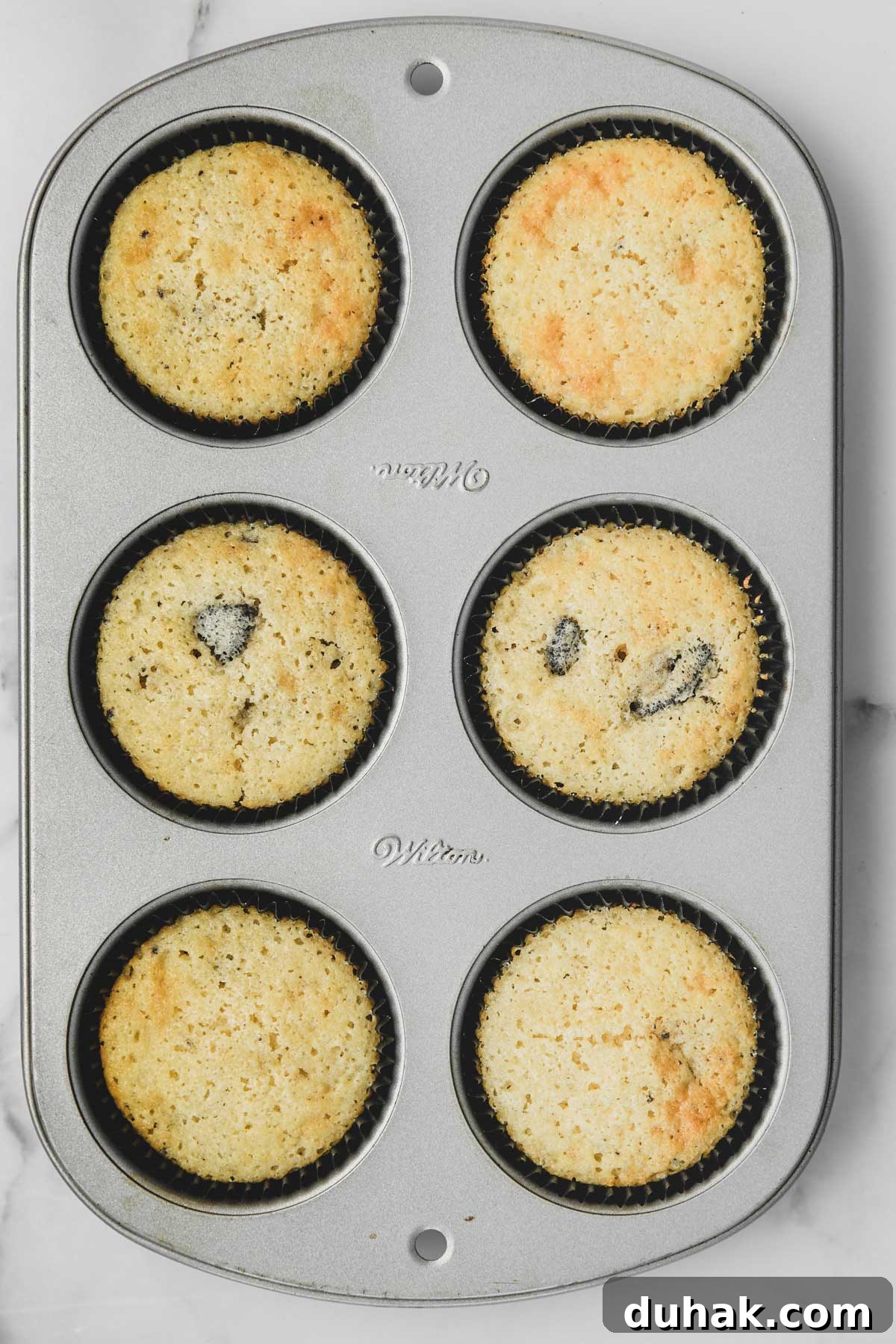 Oreo Stuffed Chocolate Cupcakes with Cream Cheese Frosting 7 baked vanilla oreo cupcakes in a muffin pan