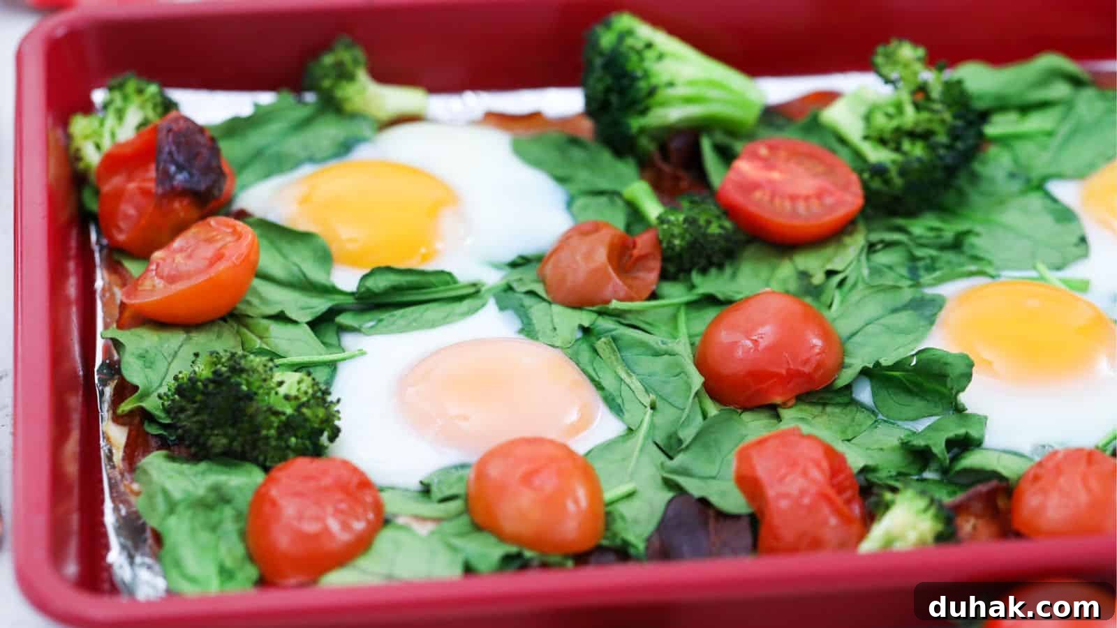 24 Low-Carb Morning Wins for Delicious, Satisfying Breakfasts 6 Sheet pan with cooked eggs, spinach, tomatoes, broccoli, and bacon.