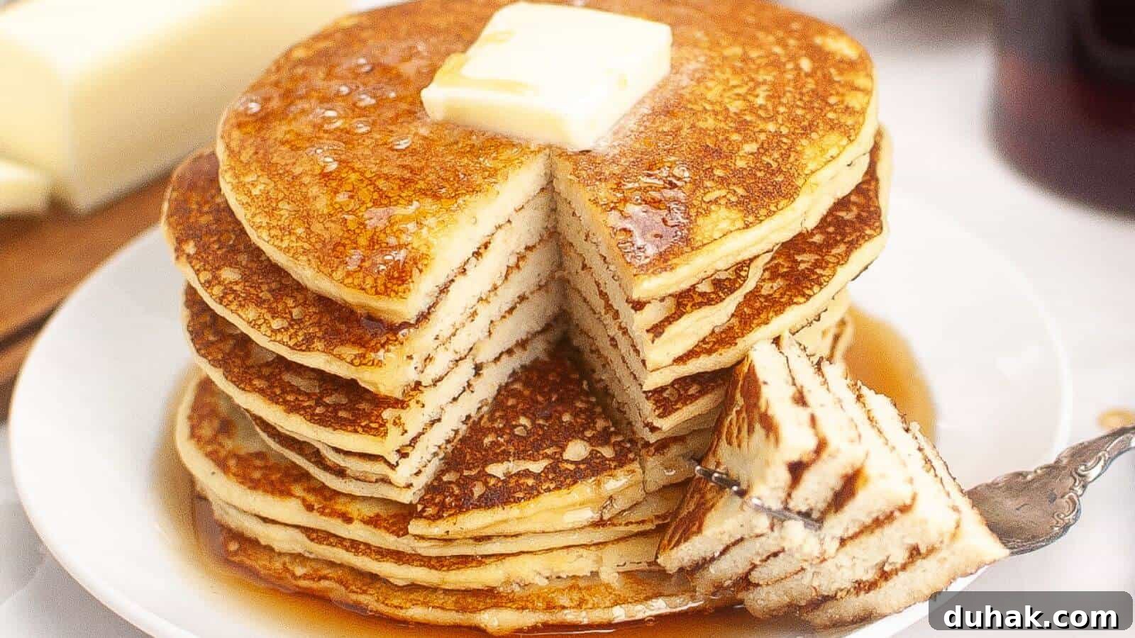 24 Low-Carb Morning Wins for Delicious, Satisfying Breakfasts 8 A stack of pancakes with a pat of butter on top, drizzled with syrup. A wedge has been cut out and is resting on a fork beside the stack.