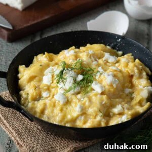 Creamy Feta and Dill Scrambled Eggs Recipe 14 Scrambled eggs in a black skillet with feta and dill on top.