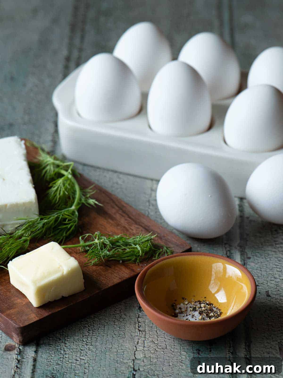 Creamy Feta and Dill Scrambled Eggs Recipe 3 Ingredients for scrambled eggs on a wood board.
