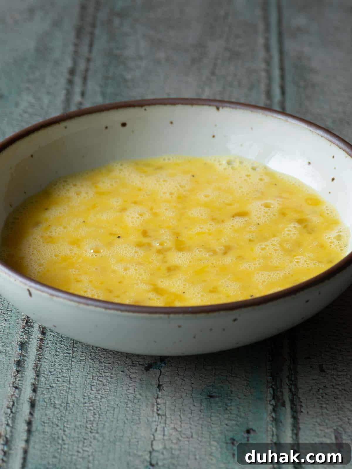 Creamy Feta and Dill Scrambled Eggs Recipe 4 Whisked eggs is a beige bowl.