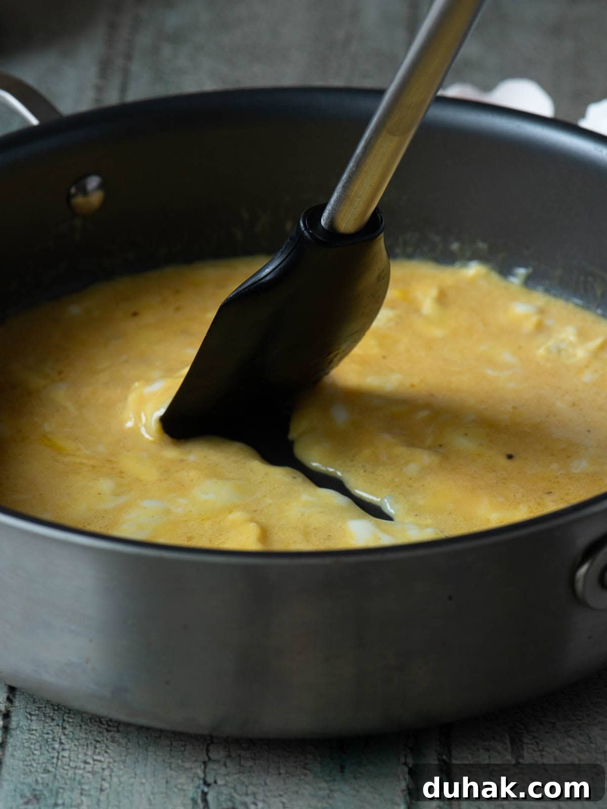 Creamy Feta and Dill Scrambled Eggs Recipe 5 Scrambled eggs being mixed with a spatula in a skillet.