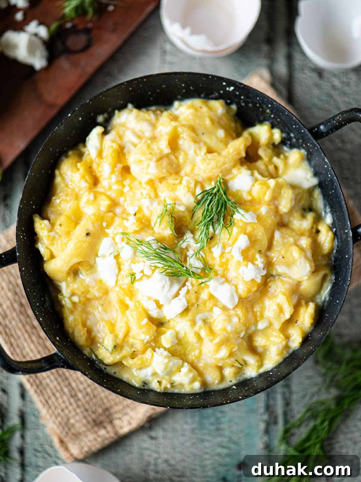 Creamy Feta and Dill Scrambled Eggs Recipe 8 Overhead of scrambled eggs in a black skillet with dill on top.