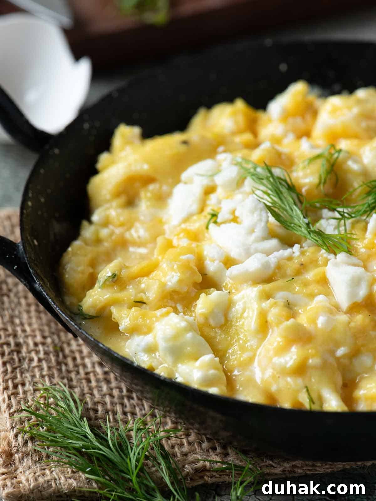 Creamy Feta and Dill Scrambled Eggs Recipe 9 Close up of scrambled eggs in a black skillet.