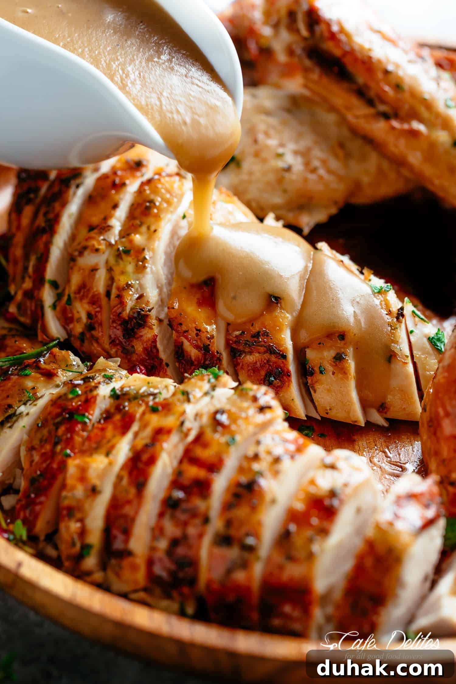close up of gravy being poured on cooked turkey