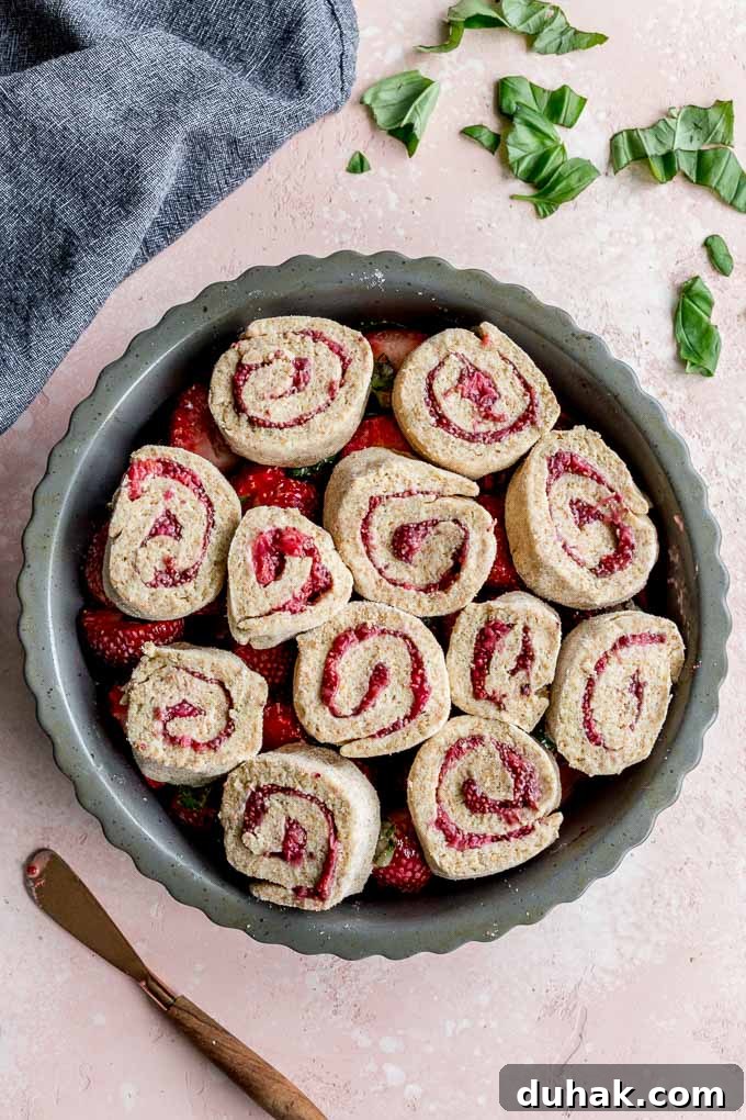 Biscuits arranged on top of the strawberry mixture in a grey pie plate.