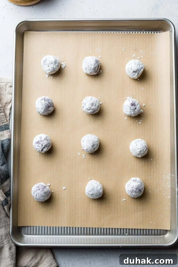 Ube Crinkle cookie dough balls on a baking sheet.