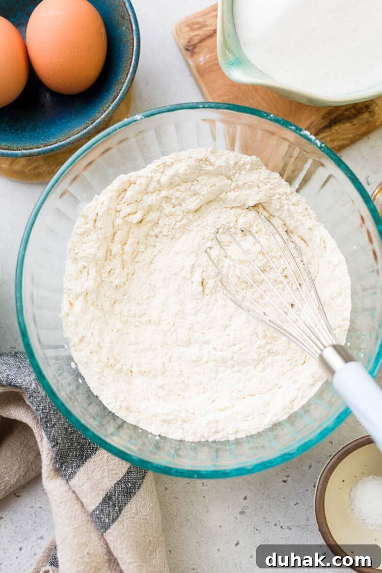 Flour in a bowl with a whisk for ube crinkle cookies.