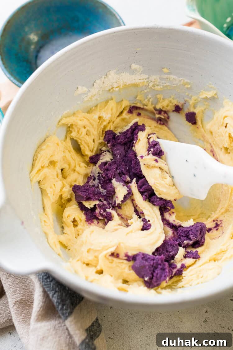 Mixing in mashed ube into ube crinkle cookie recipe.