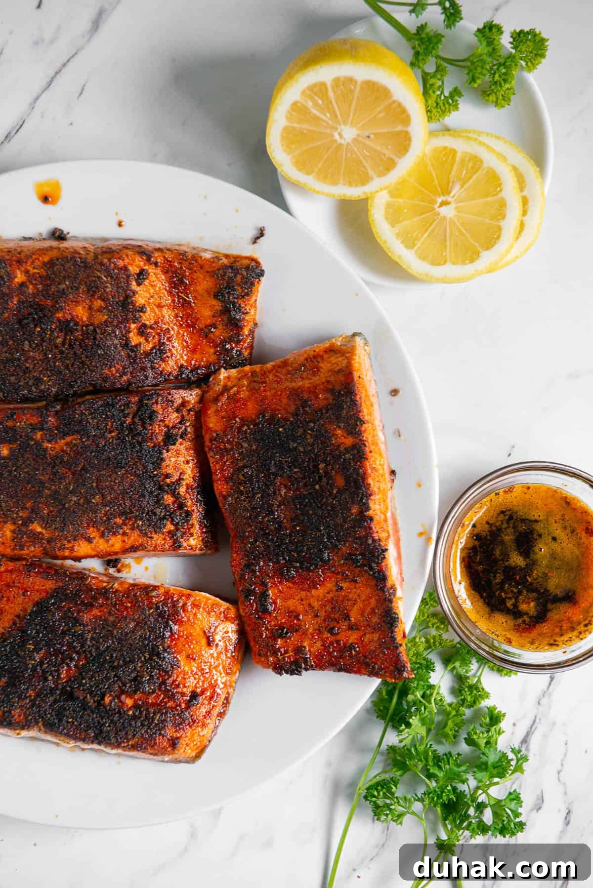 Blackened Salmon Recipe: Spicy Cajun Pan-Seared Fillets 10 blackened salmon filets on plate with lemon and butter sauce.
