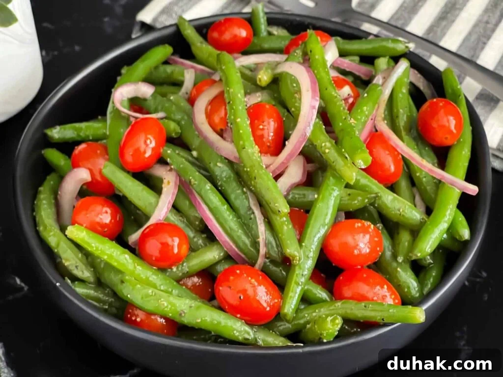 Italian green bean salad in a dark bowl on a dark surface.