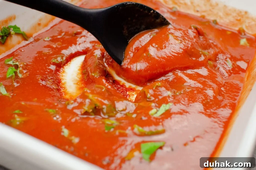 Stirring fresh chopped basil into tomato passata in a white casserole dish