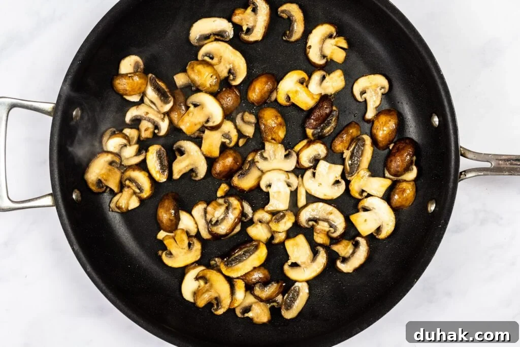 Mushrooms cooking in a skillet.