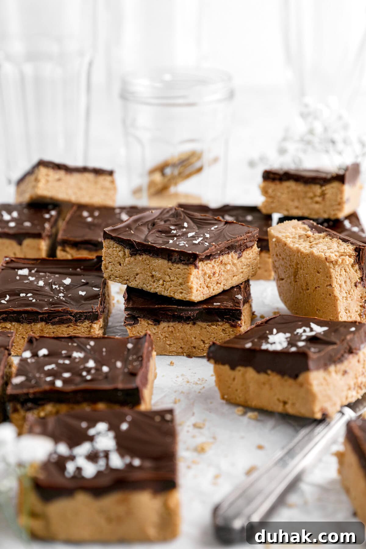 No-Bake Chocolate Peanut Butter Bars Recipe That Actually Sticks 2 peanut butter bars on parchment paper with two bars stacked.