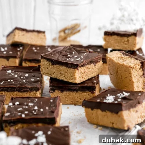No-Bake Chocolate Peanut Butter Bars Recipe That Actually Sticks 6 peanut butter bars on parchment paper with two bars stacked.