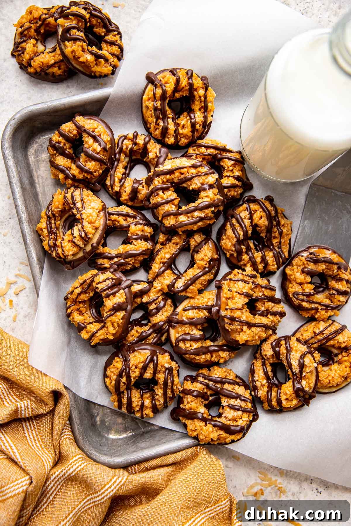 How to Make Samoas Cookies at Home — Girl Scout Copycat Recipe 2 homemade samoas cookies on parchment paper.