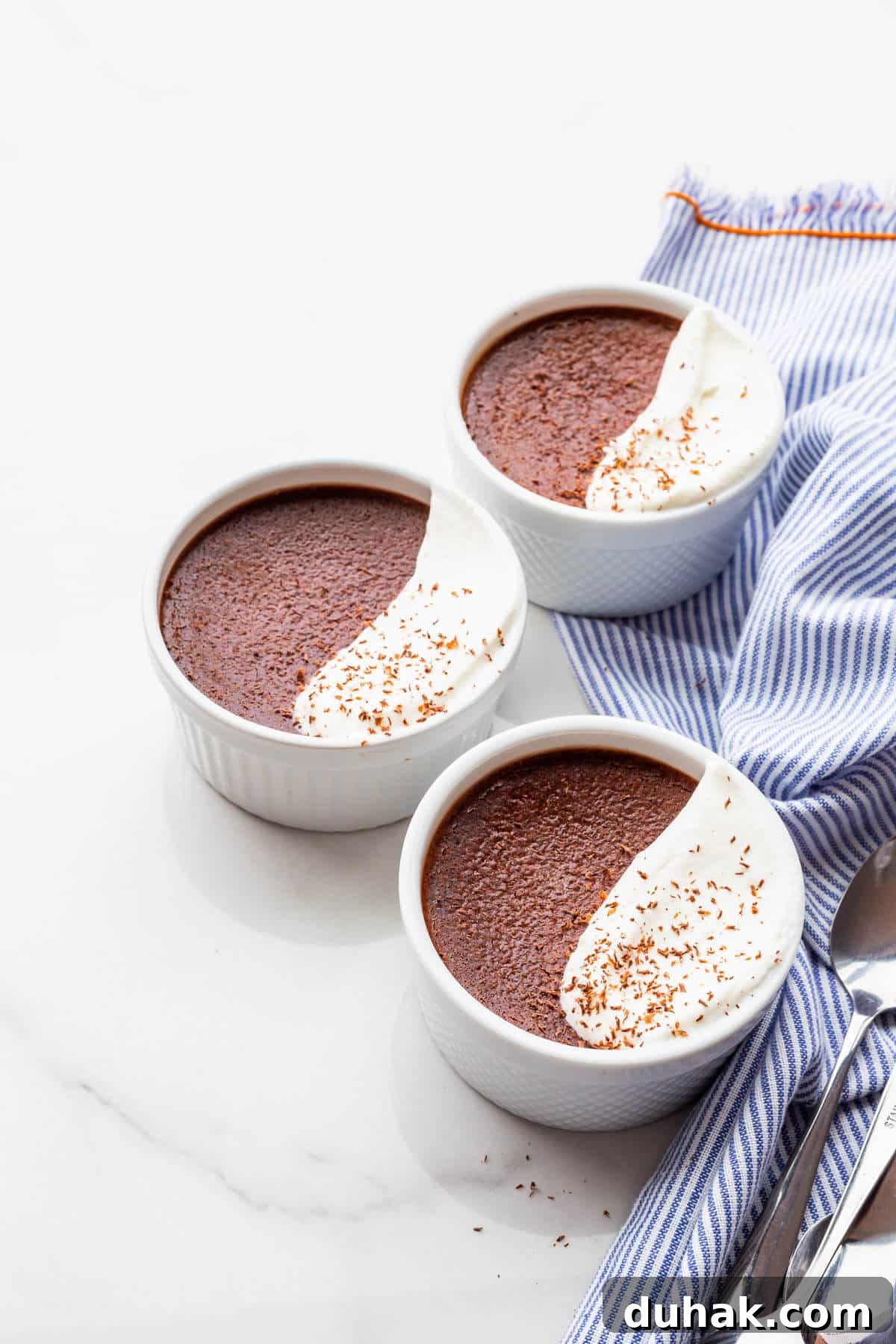 Silky Dark Chocolate Pots de Crème: Decadent French Dessert Recipe 2 Dark chocolate pots de crème desserts topped with whipped cream and grated chocolate.