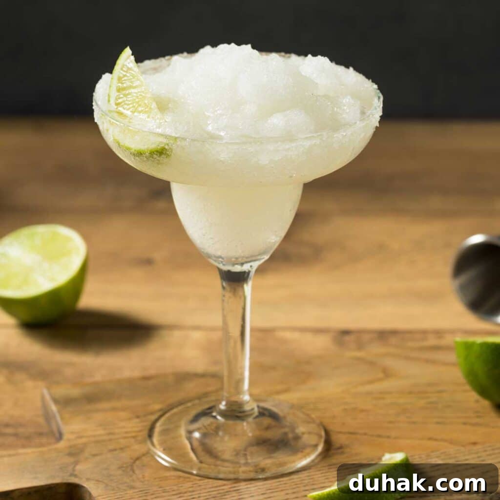 Refreshing Summer Cocktails, Mocktails & Fruity Drink Recipes 4 A glass filled with frozen margarita garnished with a lime wedge