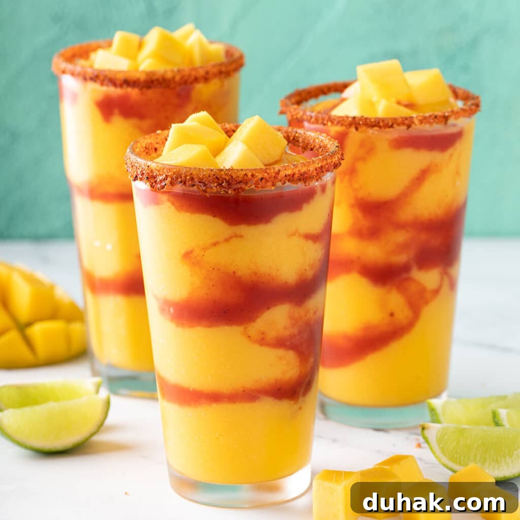 Refreshing Summer Cocktails, Mocktails & Fruity Drink Recipes 9 Three glasses filled with frozen mocktail made from mango and layered with spicy Mexican sauce.