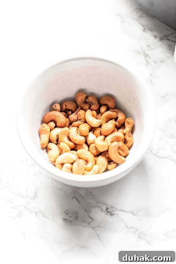 Golden brown Air Fryer cashews presented in a white bowl. A tasty snack.