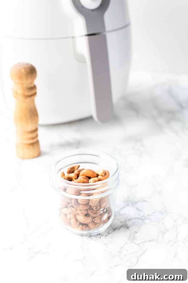 Air Fryer cashews in a glass jar. No oil needed to make golden brown and crunchy cashews yourself.