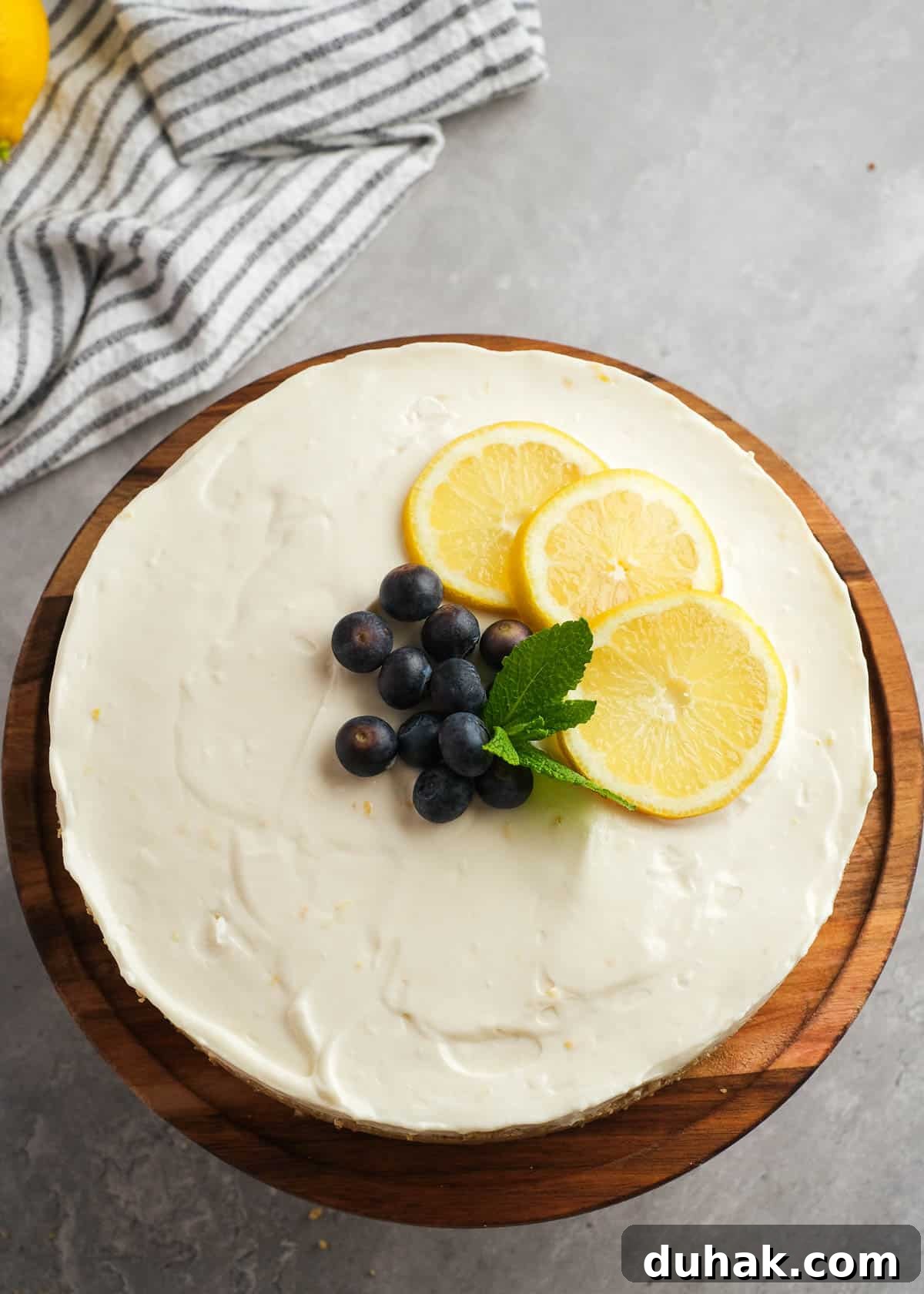 Lemon Cheesecake Recipe with Zesty Citrus Cream Filling 11 a no-bake lemon cheesecake topped with blueberries, mint leaves, and slices of lemon